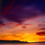 Tramonto: acqua, terra, cielo giallo rosso viola