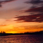 Tramonto: acqua, terra, cielo giallo rosso viola
